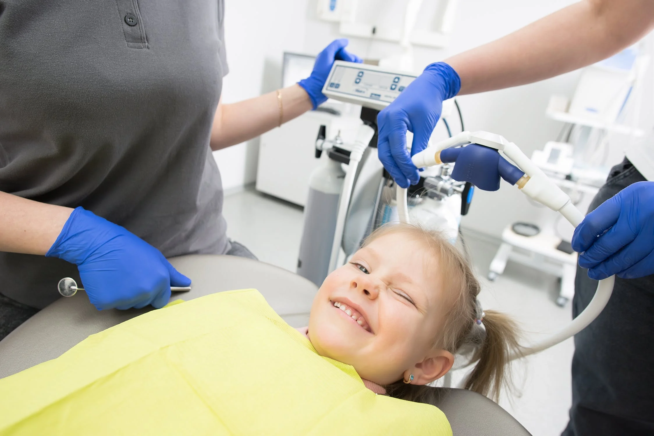 Kind sitzt lächelnd im Zahnarztstuhl